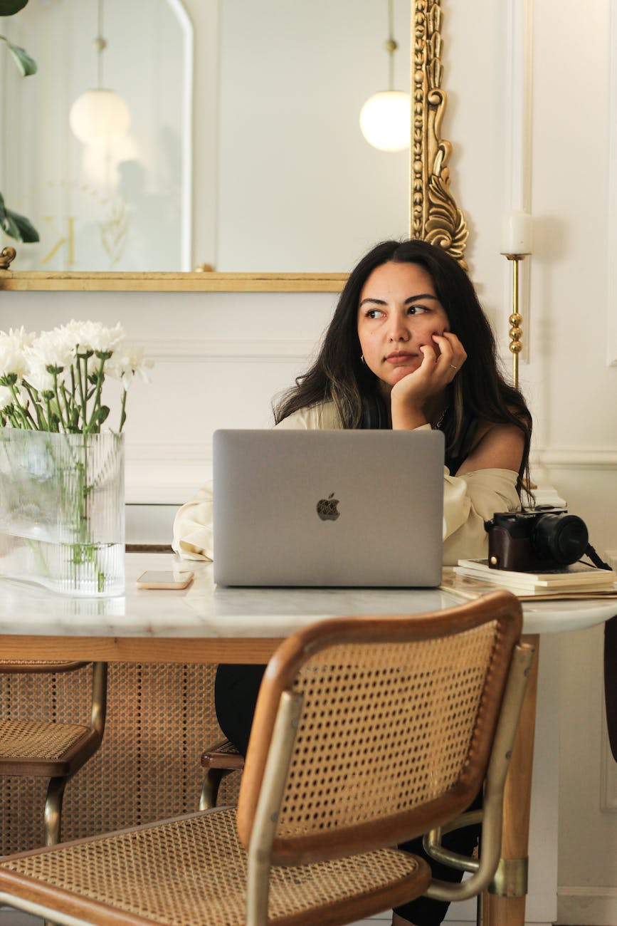 Poor client onboarding can leave new clients wondering if they've made the right choice like this woman sitting at table with laptop worrying about the purchase that she has just made.